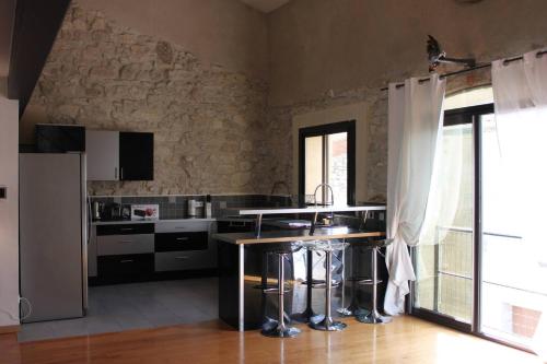 La cuisine est équipée d'un réfrigérateur et d'un comptoir avec tabourets. dans l'établissement La Galinette Family Loft, à Sigean