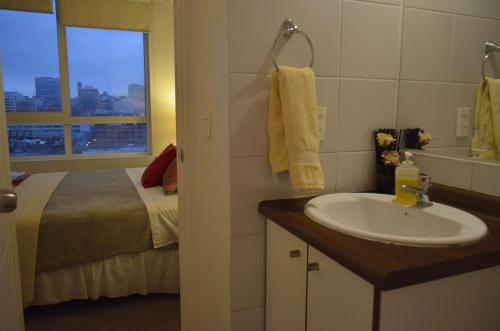a bathroom with a sink and a bed with a window at Stgo centro, Departamentos Amoblados Paz in Santiago