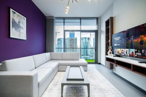 a living room with a white couch and a tv at SettlerHomes - Elegant JLT Lakefront Near Metro in Dubai