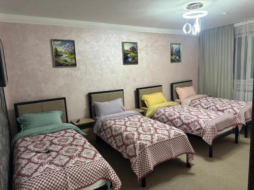 una habitación con tres camas en una habitación en Leon Hotel, en Taraz