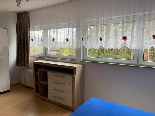 - une chambre avec trois fenêtres, une commode et un lit dans l'établissement Rosenstufen, à Heimbach