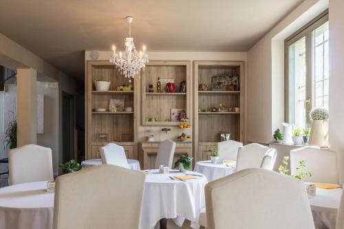 a dining room with white tables and chairs and a chandelier at La Maison De Vì in Carpaneto Piacentino