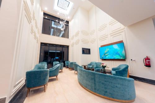 a waiting room with blue chairs and a flat screen tv at فندق واحة روز in Jeddah