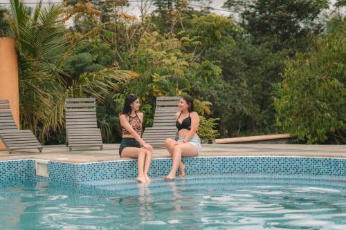 two women sitting next to a swimming pool at Eco Arazzá in Mera