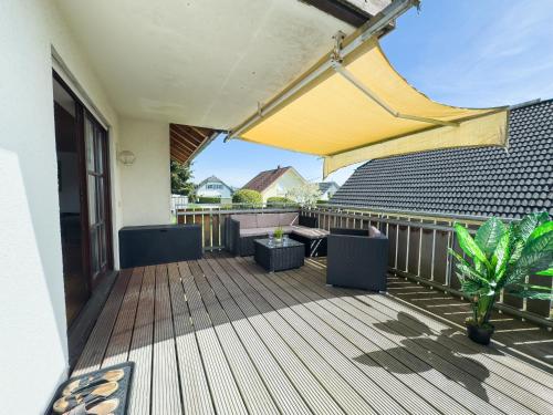 a wooden deck with chairs and a yellow umbrella at Moderne Luxus-Oase in Gailingen mit Garten, 2 Balkone, Nähe Bodensee & Rheinfall in Gailingen