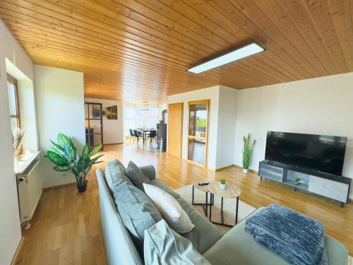 a living room with a couch and a flat screen tv at Moderne Luxus-Oase in Gailingen mit Garten, 2 Balkone, Nähe Bodensee & Rheinfall in Gailingen