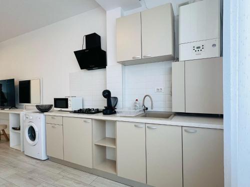 a kitchen with white cabinets and a washer and dryer at Sea vibes-Mamaia Nord in Năvodari
