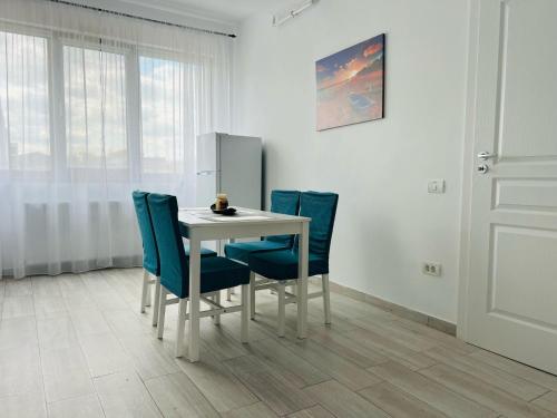 a white table with blue chairs in a room at Sea vibes-Mamaia Nord in Năvodari