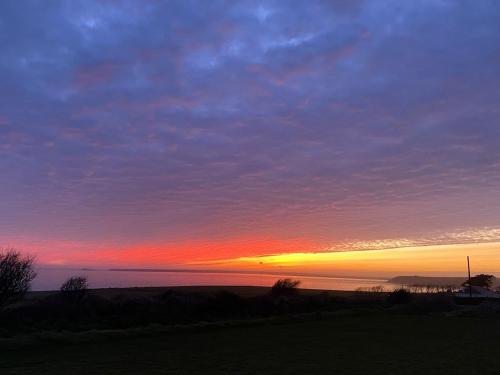 a sunset over the ocean with the sky at Ardmore's Modern Beach House in Ardmore
