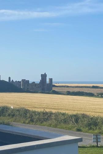 a view of a field with a castle in the distance at Ardmore's Modern Beach House in Ardmore