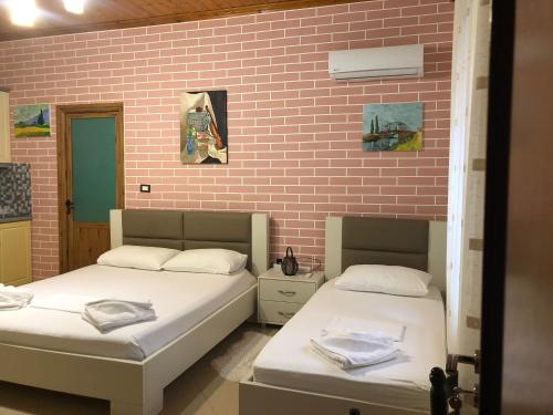 two beds in a room with a brick wall at Dhimitri's guest house in Berat