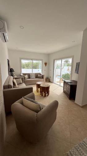 a living room with a couch and a table at Villa Paco Djerba 2 suites et piscine privée in Taguermess