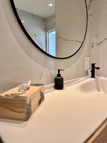 La salle de bains est pourvue d'un grand miroir et d'un lavabo. dans l'établissement Le Clos de la Côte Sauvage, à Piriac-sur-Mer