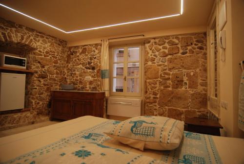 a bedroom with a bed and a stone wall at Suite Principe Umberto Alghero Centralissima in Alghero
