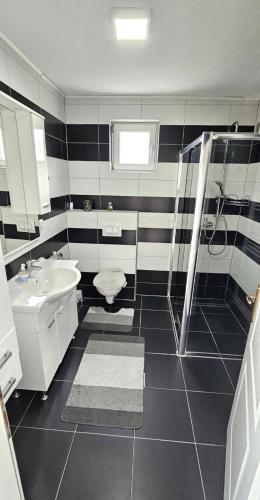 a black and white bathroom with a sink and a shower at Apartman STARI GRAD in Bihać