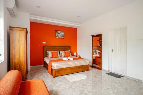 an orange bedroom with a bed and an orange wall at Spacious Eco Guest House Colombo in Sri Jayewardenepura Kotte