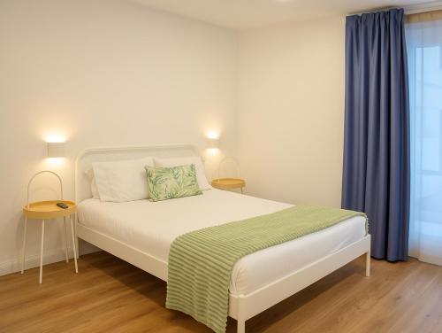 a bedroom with a white bed with blue curtains at Magnolia Suites & Stays in Porto