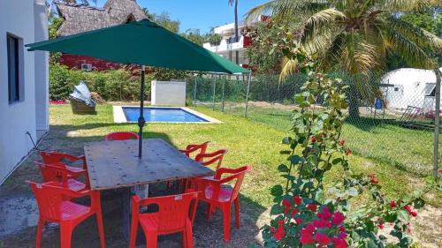 a table with red chairs and a green umbrella at Apolo Apartment, near the beach with pool in Barra de Navidad