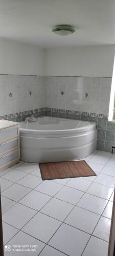 La salle de bains est pourvue d'une baignoire blanche et de carrelage. dans l'établissement La ferme des gribouts, à La Flamengrie