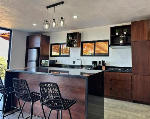 a kitchen with a bar with chairs and a sink at Cabaña Nurela in Mazamitla