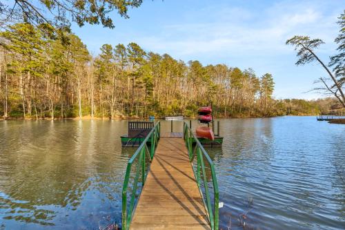 a dock with a boat on it on a lake at LUXE Lake Adger-Lakefront Home, Private Dock, Hot Tub, Fire Pit, Canoe, Epic Mtn & Lake Views, Universal EV Station in Mill Spring