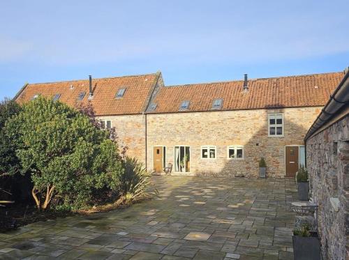 a large brick building with a courtyard in front of it at The Byre - Luxury Barn, near Wells, Somerset, pool, gym in Wells