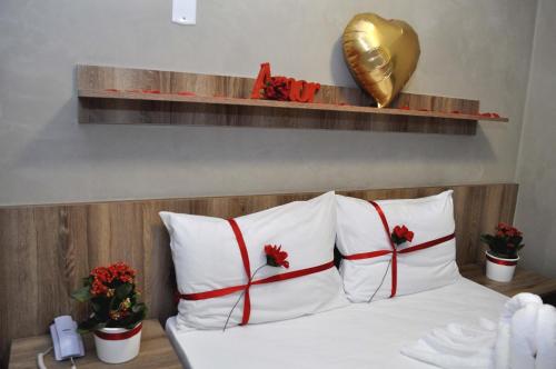 a bed with white pillows and a gold heart on the wall at Hotel Pousadas Club in Sorocaba