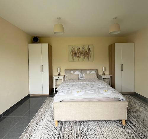 a bedroom with a large bed and two cabinets at Luxury Apartment Heald Green in Handforth