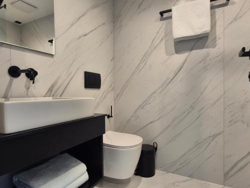 a white bathroom with a sink and a toilet at Meraviglia Boutique Hotel in Sarandë
