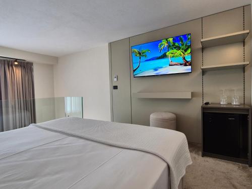 a bedroom with a white bed and a flat screen tv at Meraviglia Boutique Hotel in Sarandë