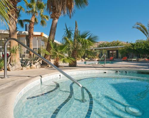 a swimming pool with palm trees in a resort at Hope Springs Resort in Desert Hot Springs