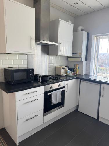 a kitchen with white cabinets and a stove top oven at Spacious 2 bedroom flat in Newcastle w Free parking in Kenton
