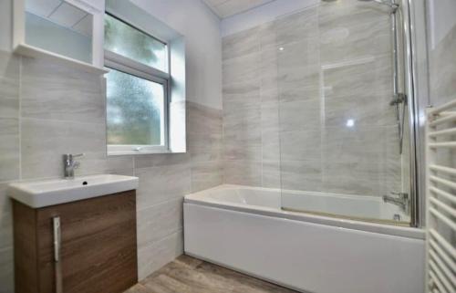 a bathroom with a tub and a sink and a shower at Spacious 2 bedroom flat in Newcastle w Free parking in Kenton