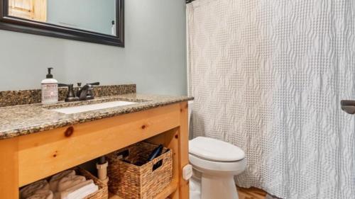a bathroom with a toilet and a sink and a mirror at 5 Pines on Ossie by Woods to Water in Breezy Point