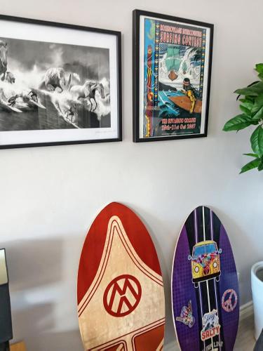 a group of surfboards on a wall with framed pictures at Sea Surf in Bangor