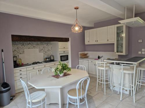 a kitchen with a white table and white chairs at Maison à la campagne in Tollent