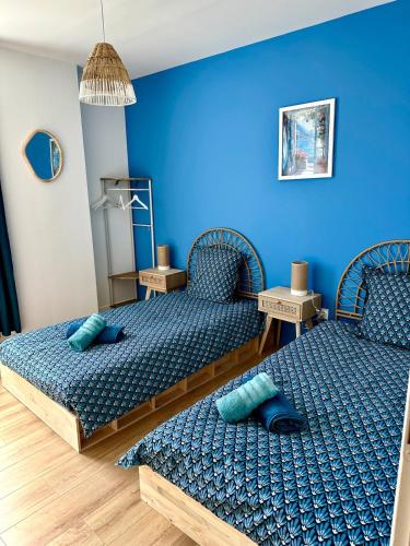 two beds in a room with blue walls at La Grèce - Appartement chaleureux en hypercentre in Saint-Quentin