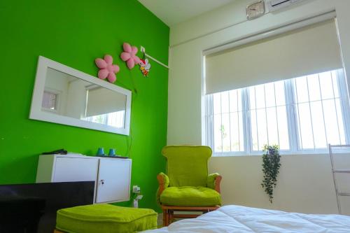 a green bedroom with a chair and a mirror at Spacious Eco Guest House Colombo in Sri Jayewardenepura Kotte
