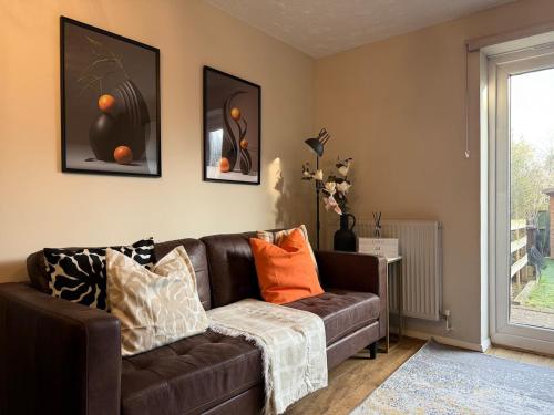 a living room with a brown leather couch with pillows at Beautifully renovated 2bed home in North Stifford