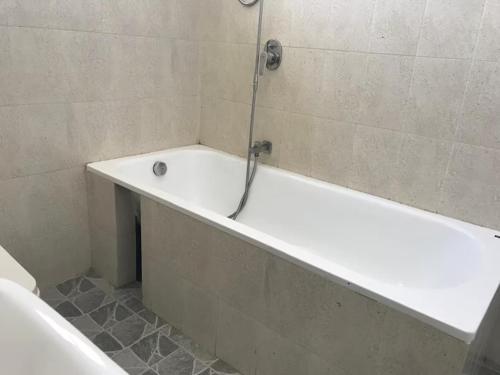 a bath tub with a shower in a bathroom at Spacious Eco Guest House Colombo in Sri Jayewardenepura Kotte