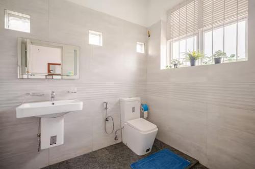 a white bathroom with a sink and a toilet at Spacious Eco Guest House Colombo in Sri Jayewardenepura Kotte