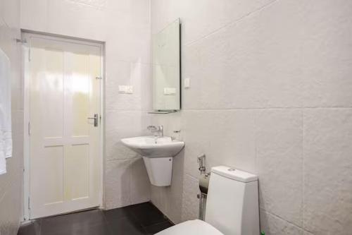 a white bathroom with a toilet and a sink at Spacious Eco Guest House Colombo in Sri Jayewardenepura Kotte