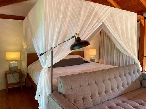 a bedroom with a canopy bed with white curtains at Kubla Khan - Chirripó Mountain Riverfront Retreat in Rivas