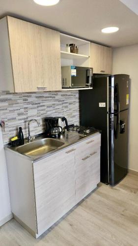a kitchen with a sink and a black refrigerator at Toscana LOFT - Apartasuites in Bogotá