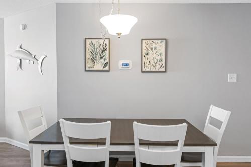 a dining room with a table and white chairs at Ocean View 2BR2BA Top-Floor Condo w Balcony & Bay Sunset Views in Ocean City