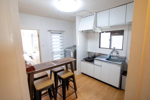 a kitchen with white cabinets and a table and chairs at Mitomi inn 京急蒲田駅 in Tokyo