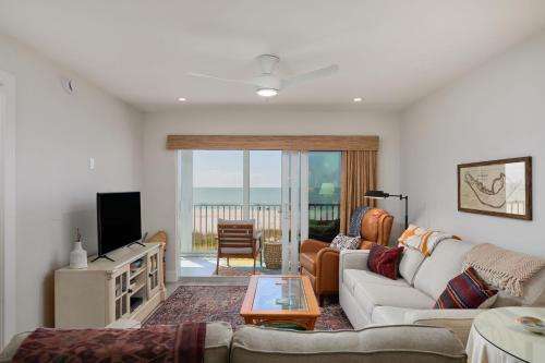 a living room with a couch and a tv at Spectacular Gulf Front Residence in Exclusive Sanibel Surfside in Sanibel