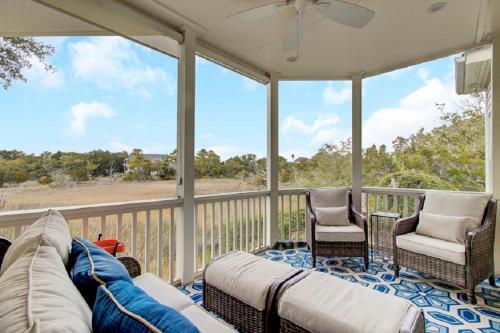 a screened in porch with a couch and chairs at Seagrass Lane 25 by Wild Dunes, Home with Marsh View and Resort Amenity Access in Isle of Palms