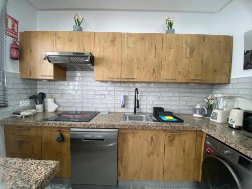 a kitchen with wooden cabinets and a sink and a dishwasher at Cabo Beach Home 1 in Cabo Negro