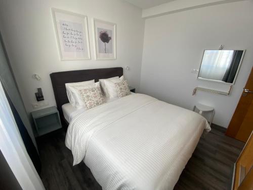 a small white bedroom with a white bed with pillows at Cabo Beach Home 1 in Cabo Negro